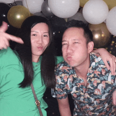 Happy couple having fun at GIF booth with birthday balloon backdrop