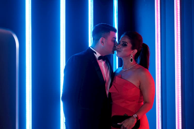 Romantic couple kissing at photo booth with red and blue neon lights