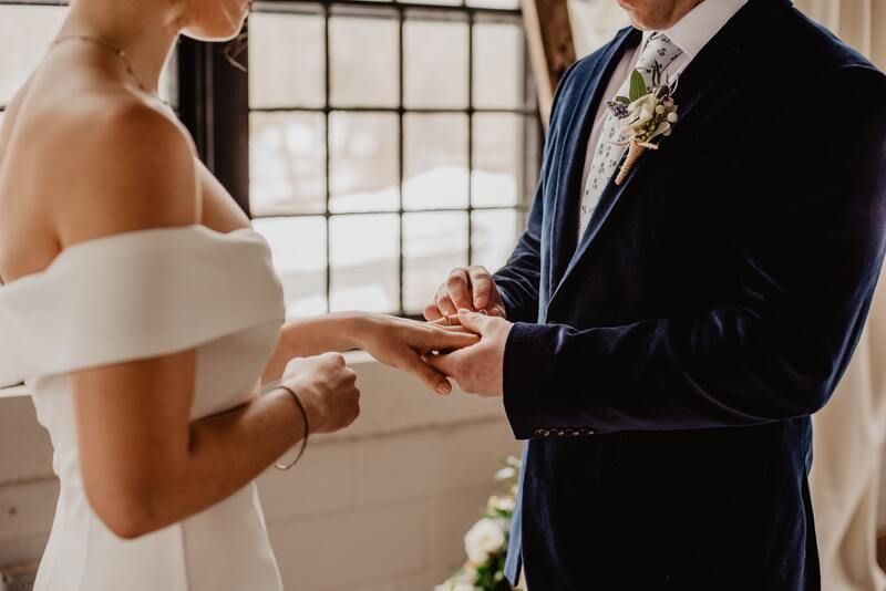 Man putting wedding ring on woman at virtual wedding ceremony