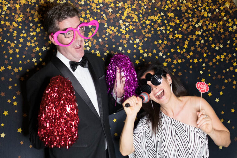 Well dressed couple posing with photo booth props