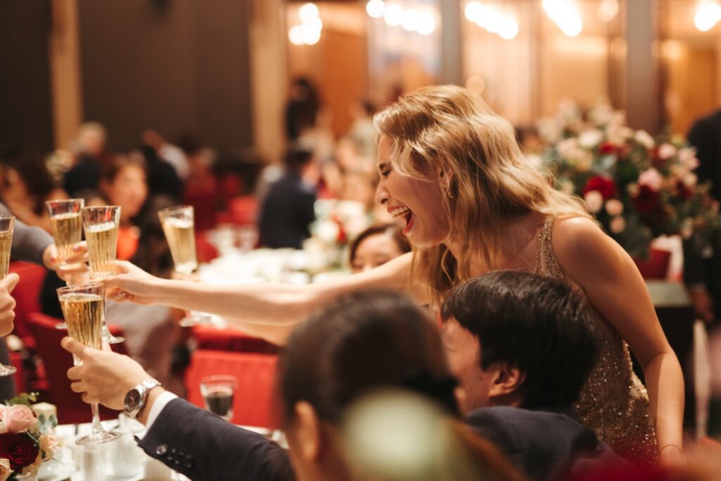 Woman cheering with guests at the dinner table at the wedding reception toasting wedding ceremony photography photograph