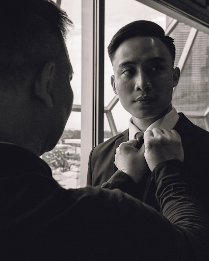 Groom having bow-tie done by friend before wedding photoshoot photography